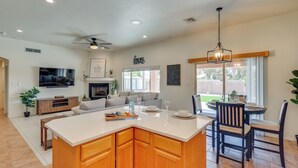 A spacious kitchen with a central island, a dining area with a round table, and a living room with a sofa and a flat-screen TV. - 1 Mi to Golf Course: Yuma Oasis w/ Furnished Patio (Yuma)