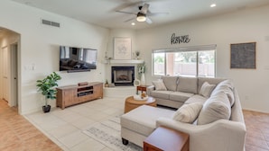 A living room with a flat-screen TV, a fireplace, a ceiling fan, and a large window. - 1 Mi to Golf Course: Yuma Oasis w/ Furnished Patio (Yuma)