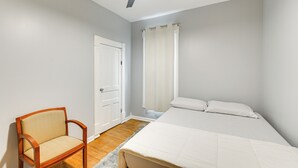 Ein Schlafzimmer mit Bett, Stuhl, Tür und einem Fenster mit Vorhängen.