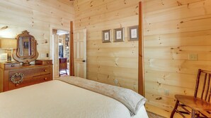 A wooden-paneled room with a bed, dresser, mirror, and framed pictures on the wall. - 4 Mi to Fall Branch Falls: Peaceful Cabin w/ Deck (Cherry Log)