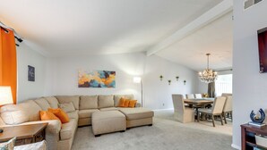 A living room with a sectional sofa, a dining table with chairs, and a chandelier. - Deck & Seasonal Pool: Spacious Home Near Buffalo! (Buffalo)
