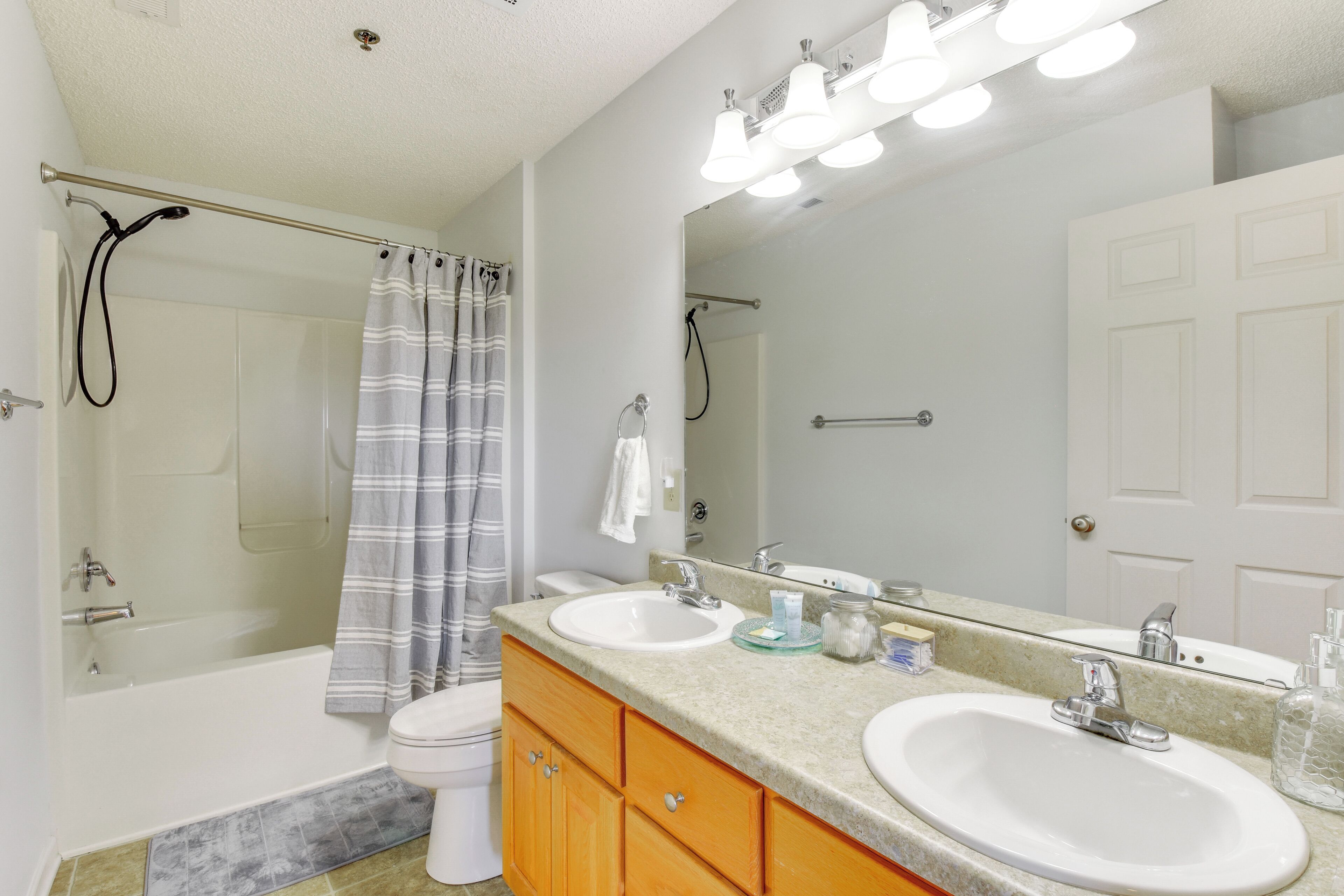 Une salle de bain avec une baignoire, deux lavabos, une douche et un grand miroir.