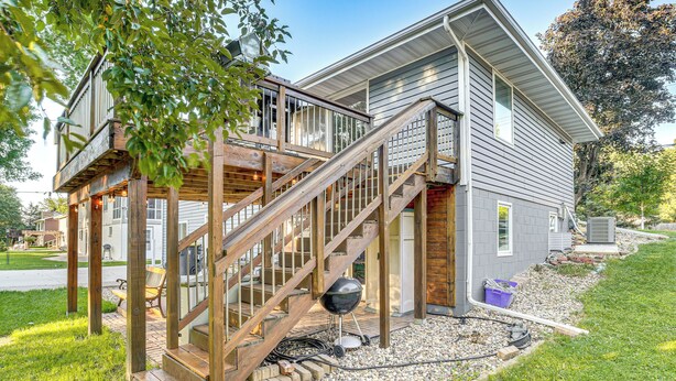 A two-story house with a wooden deck and a staircase leading to the second floor. - Walk to Spring Lake w/ Waterpark: Family Retreat! (North Mankato)