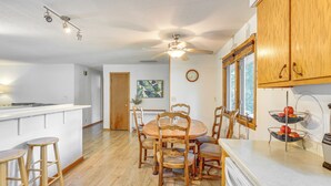 A kitchen with wooden cabinets, a dining table with chairs, a ceiling fan, and a window with blinds. - Walk to Spring Lake w/ Waterpark: Family Retreat! (North Mankato)