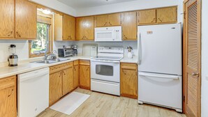 A kitchen with wooden cabinets, a microwave, a stove, a sink, and a refrigerator. - Walk to Spring Lake w/ Waterpark: Family Retreat! (North Mankato)