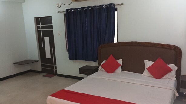 A bedroom with a bed, a wardrobe, and a window with curtains. - Ppmotel alibag  (Alibag)