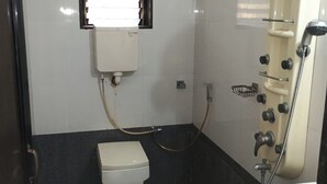 A compact bathroom with a toilet, a pedestal bidet, a sink, and a shower unit. - Ppmotel alibag  (Alibag)