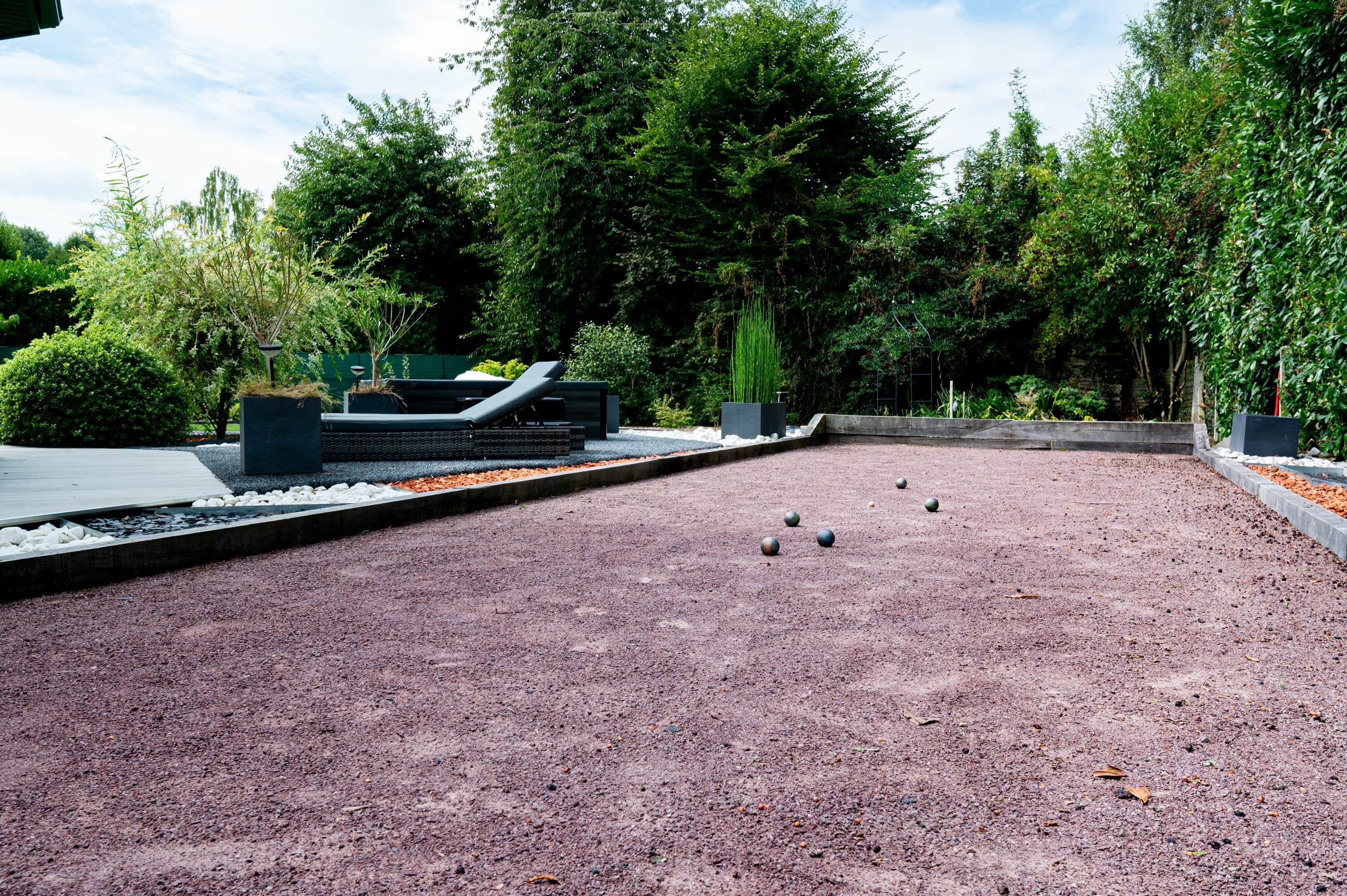 A gravel croquet court with a seating area and surrounding greenery.