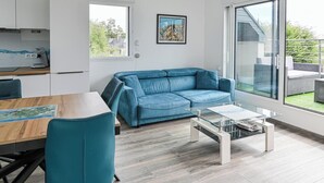 Un soggiorno moderno con un divano blu, un tavolo da pranzo in legno e un tavolino da caffè in vetro.