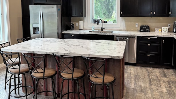 A kitchen with a marble island, black cabinets, and a window with a view of trees. - Cozy, beautiful, family friendly, 3-bedroom, newly built cabin on Lake Latoka (Alexandria)