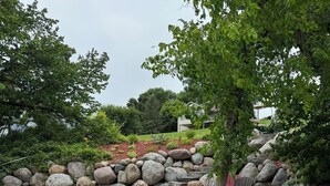 A boat docked at a wooden pier, surrounded by a landscaped garden with rocks, a bench, and a tree. - Cozy, beautiful, family friendly, 3-bedroom, newly built cabin on Lake Latoka (Alexandria)