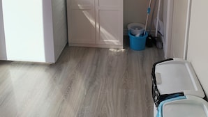 Un cuarto de lavado con lavadora, secadora, armario y productos de limpieza.
