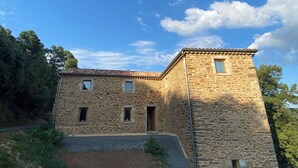 Un edificio de piedra con tejado de tejas, dos ventanas y una puerta.