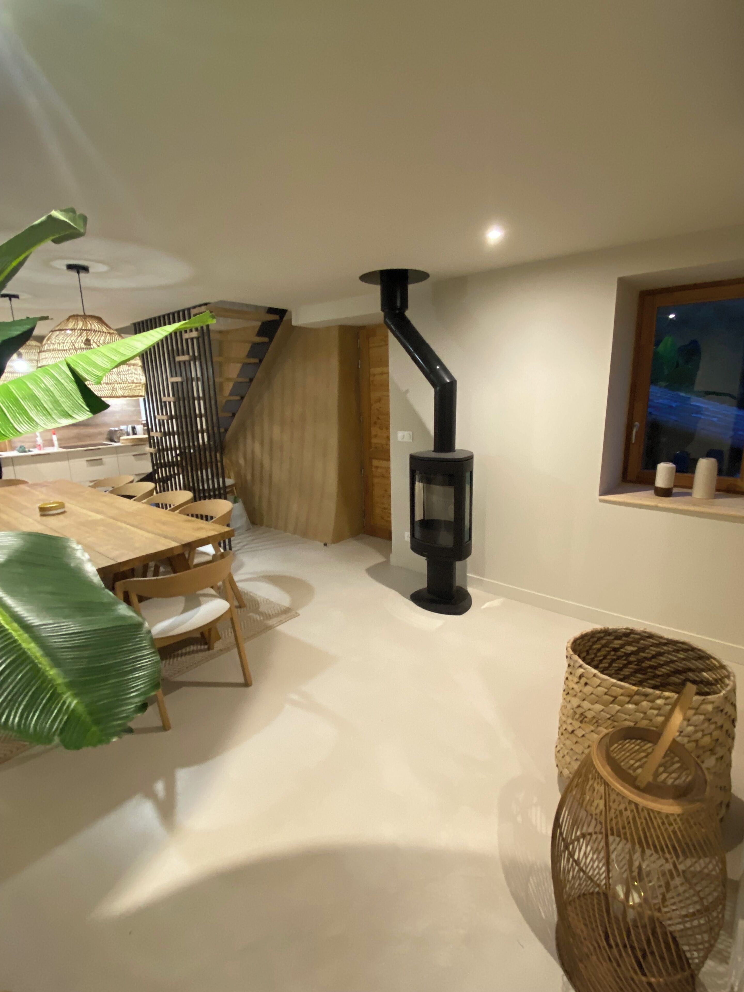 A modern kitchen with a wooden table, chairs, and a black stove.