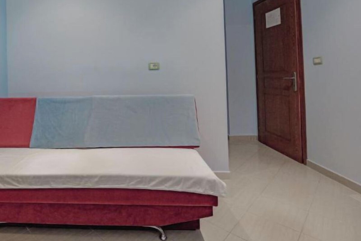 A room with a bed, a door, and light blue walls.