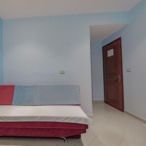 A room with a bed, a door, and light blue walls. - Hotel Divo Palace (Ksamil)
