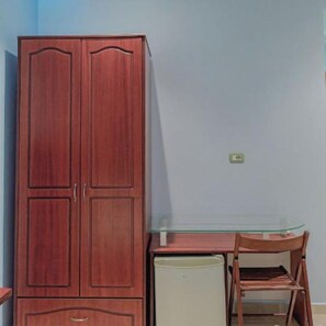 A room with a wooden wardrobe, a small table with a chair, and a refrigerator. - Hotel Divo Palace (Ksamil)