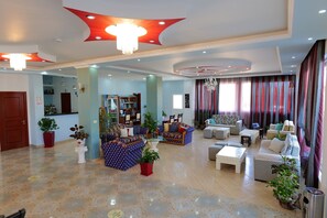 A spacious living area with multiple seating options, a chandelier, and a variety of plants. - Hotel Divo Palace (Ksamil)