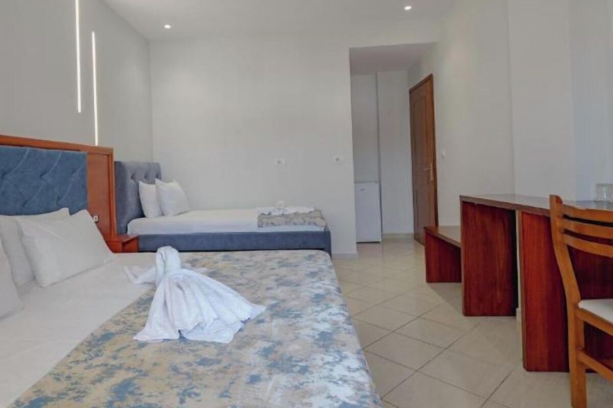 A hotel room with a bed, a small desk, and a chair.