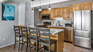 A modern kitchen with wooden cabinets, stainless steel appliances, and pendant lighting.