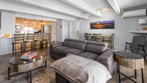 A modern living room with a sectional sofa, a coffee table, and a dining area with chairs and a table.