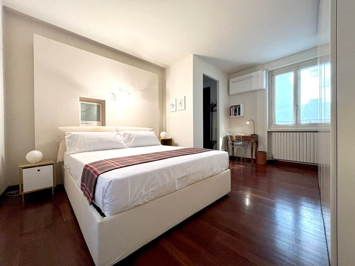 Una camera da letto con un letto, comodini, uno specchio, un termosifone e una finestra.