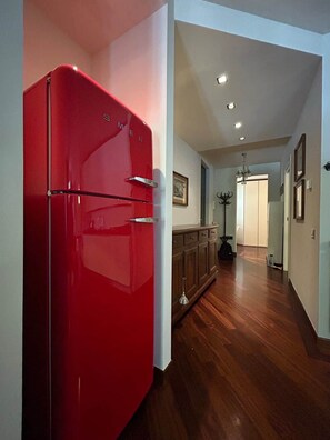 Une cuisine avec un réfrigérateur rouge, des armoires en bois et un lustre.