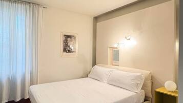 Ein Schlafzimmer mit Bett, Nachttisch, Wandlampe und einem gerahmten Bild.