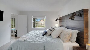 A bedroom with a bed, a window, and a wall-mounted lamp.