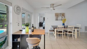 A modern kitchen with a dining area, a ceiling fan, and a view of a swimming pool.