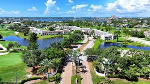 Un campo de golf con un lago, rodeado de edificios y follaje.