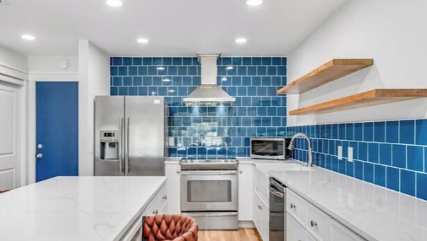 Una cocina moderna con baldosas azules, electrodomésticos de acero inoxidable y una isla de madera.