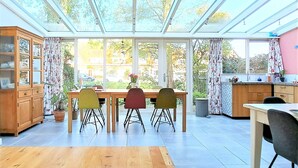 Une cuisine lumineuse avec une grande fenêtre, une table à manger avec des chaises et un buffet en bois.