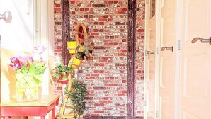 Un couloir avec un mur en briques, un sol carrelé et une porte ornée d’une enseigne jaune.