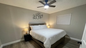 Una camera da letto con un letto, comodini, una ventola a soffitto e un lampadario a parete.