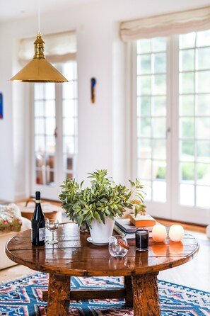 Une table ronde en bois, sur laquelle se trouvent un pot de fleurs, une bouteille de vin et des verres.