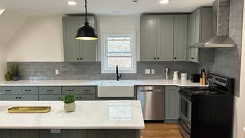 Una cocina moderna con una isla central, electrodomésticos de acero inoxidable y armarios color verde claro.