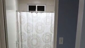 Une salle de bain avec un rideau de douche, des toilettes et un carrelage au sol.