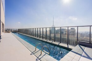 Una piscina en la azotea con barandilla de cristal, con vistas a la ciudad.