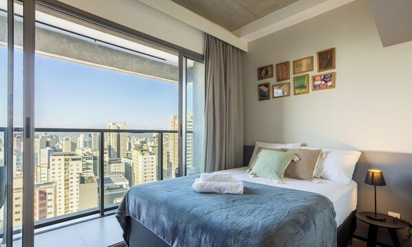 A modern bedroom with a large window, a neatly made bed, and a city view. - Charming, Well-located apt in Paraiso Onp2021 (São Paulo)