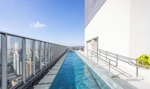 A swimming pool with glass walls, offering a view of the cityscape. - Charming, Well-located apt in Paraiso Onp2021 (São Paulo)