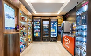 A well-lit retail area with refrigerated and frozen food sections, a Zahil appliance, and a Kibon vending machine. - Charming, Well-located apt in Paraiso Onp2021 (São Paulo)