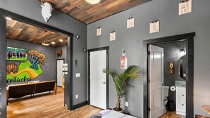 A modern bedroom with a wooden ceiling, a bed with a blue and white duvet, a small potted plant, and a wall with a Kentucky Wildcats mural. - Kentucky State of Mind - Interactive Puzzle Stay (Frankfort)