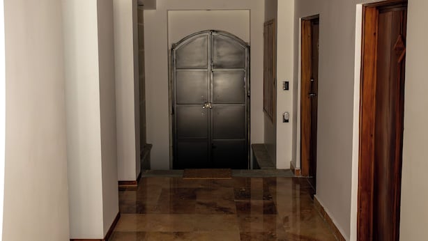 Un couloir avec un plafond en bois, une grande porte en arc de cercle et un sol carrelé poli.
