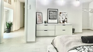 A modern bedroom with a bed, a dresser, and wall-mounted lighting. - Spacious, 2-bedroom apartment in Budapest with AC & Netflix (Budapest)