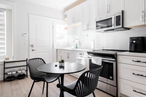A modern kitchen with white cabinets, a black stove, and a round table with two chairs.