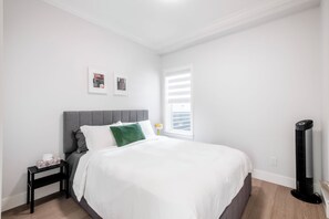 Un dormitorio con cama, mesita de noche, lámpara y un calentador eléctrico.