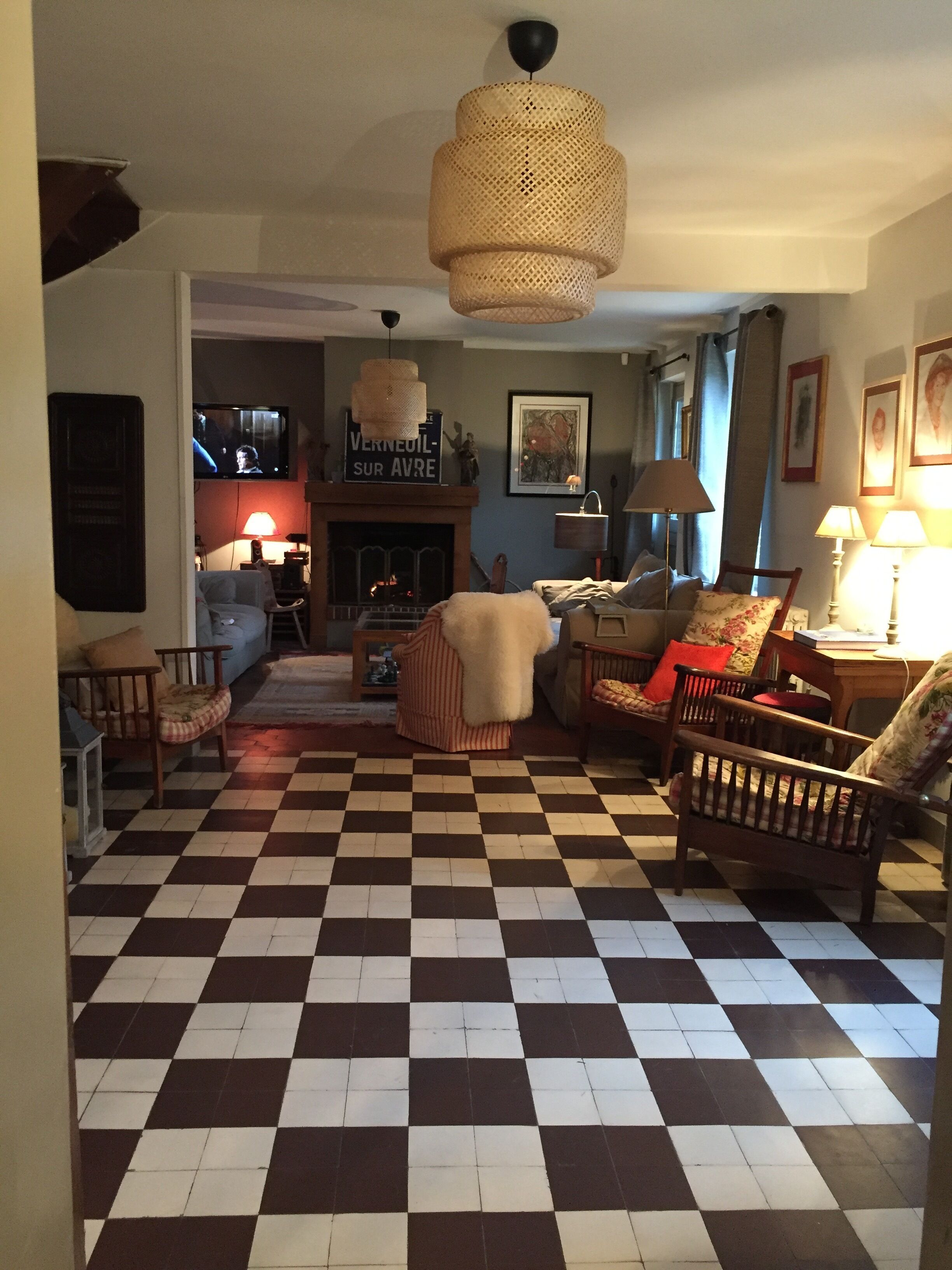 Un salon avec un sol à carreaux, une cheminée et un téléviseur.