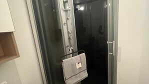 Une salle de bain avec une douche à parois de verre, un porte-serviettes avec une serviette et un distributeur de savon sur le lavabo.