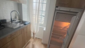 Une cuisine équipée d’un lave-vaisselle intégré, d’un évier et d’une fenêtre avec des stores.
